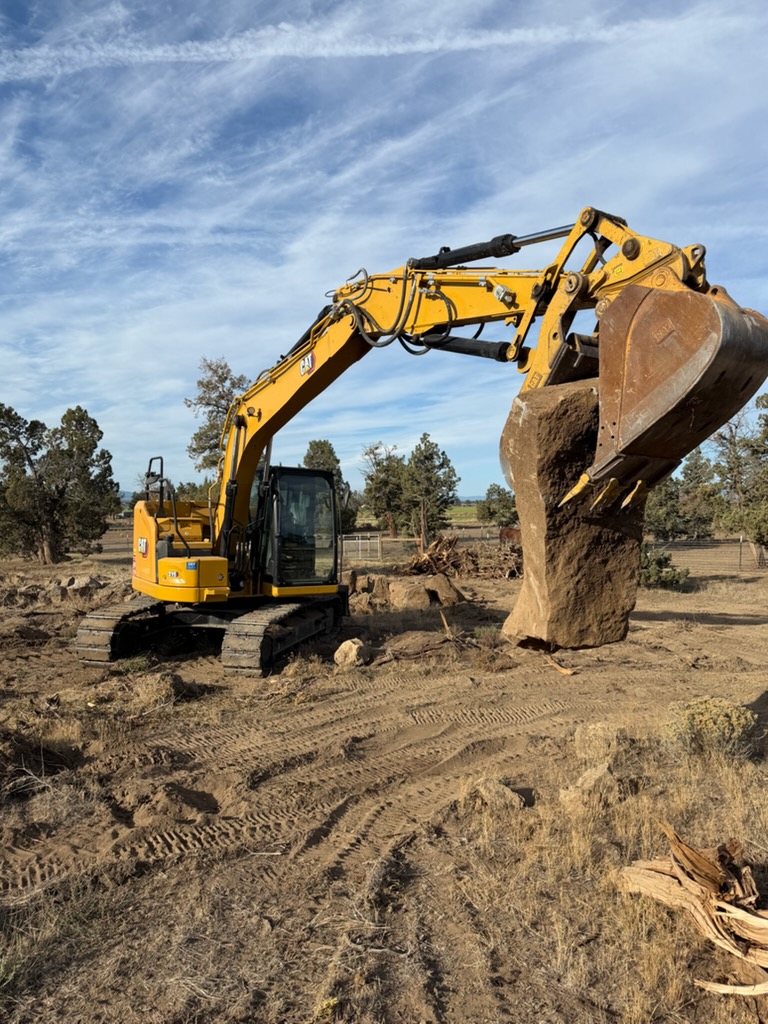 Byrd Land Co. excavator removing a large boulder from a property in Central Oregon